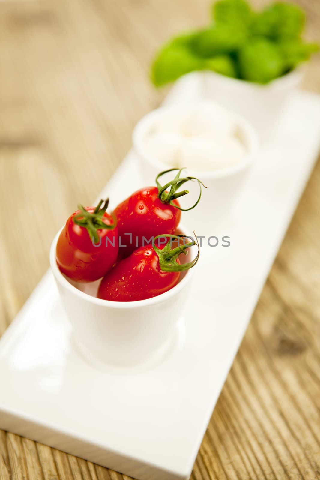 tasty tomatoes mazarella and basil on plate on wooden background