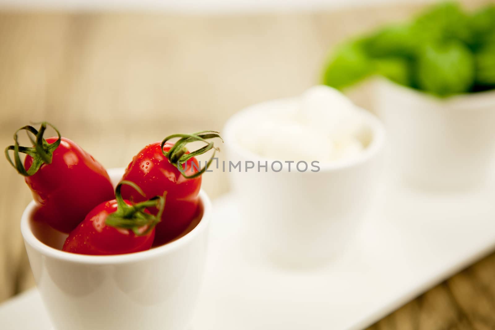 tasty tomatoes mazarella and basil on plate on wooden background