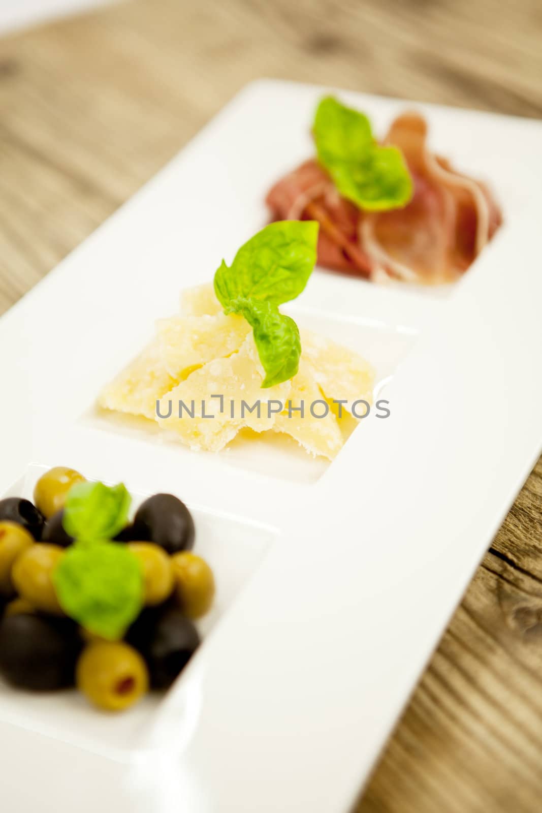 deliscious antipasti plate with parma parmesan olives on wooden background