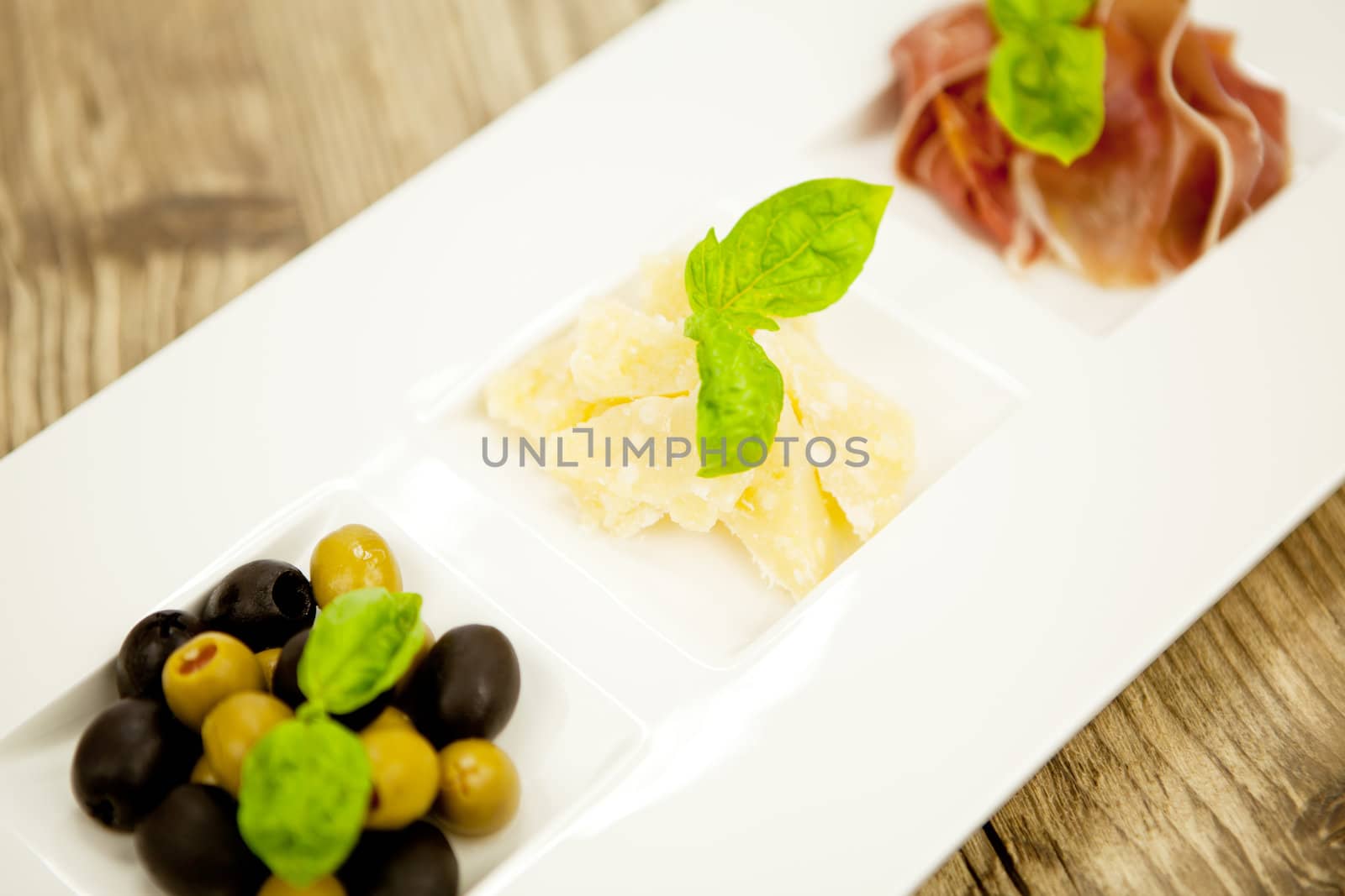 deliscious antipasti plate with parma parmesan olives on wooden background