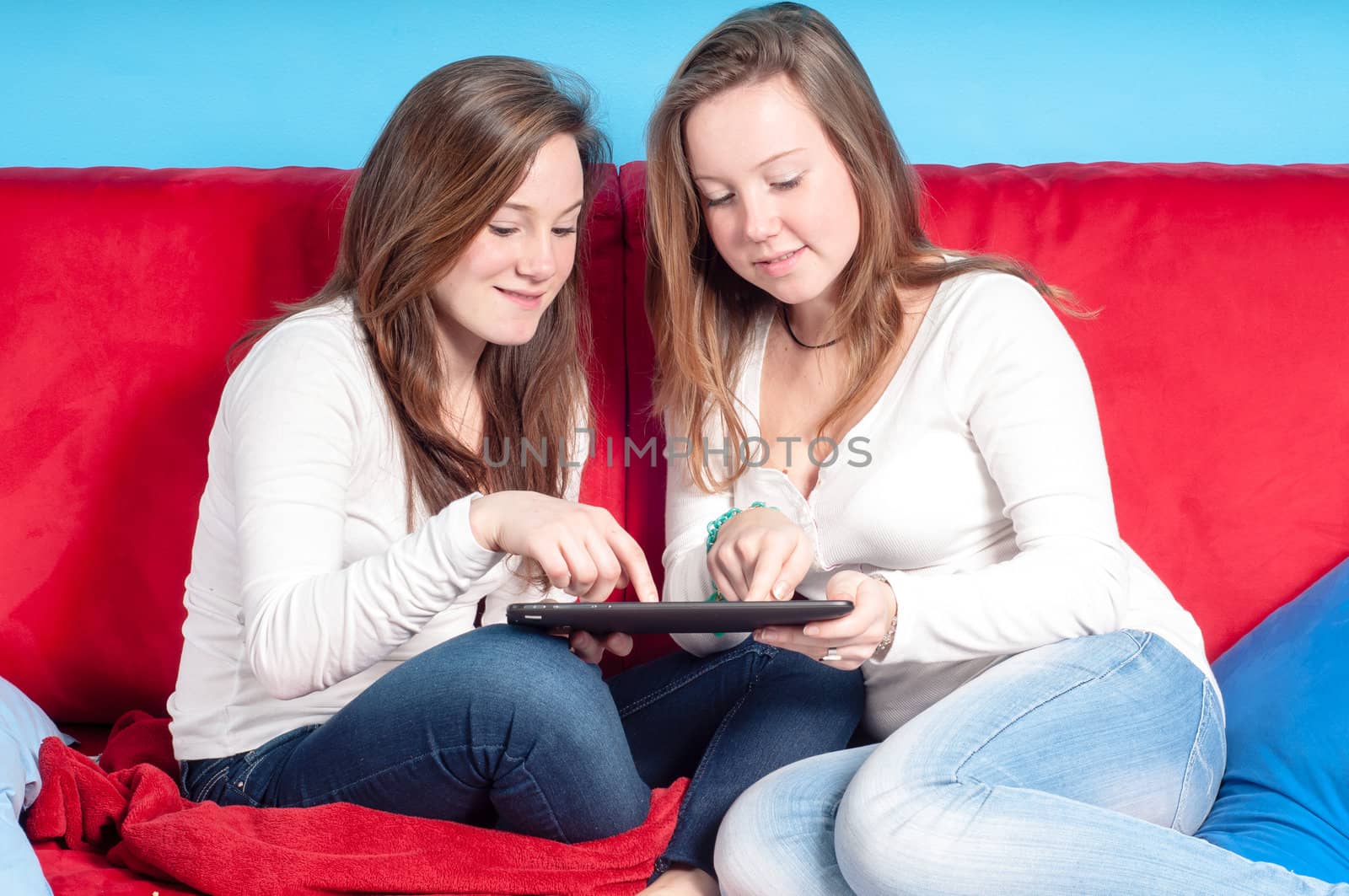 happy teenagers using tablet on the couch at homein the living room