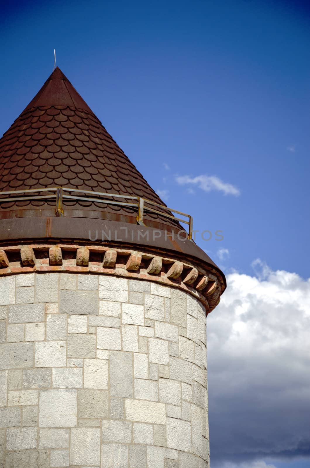 Round castle tower close view with clouds behind.