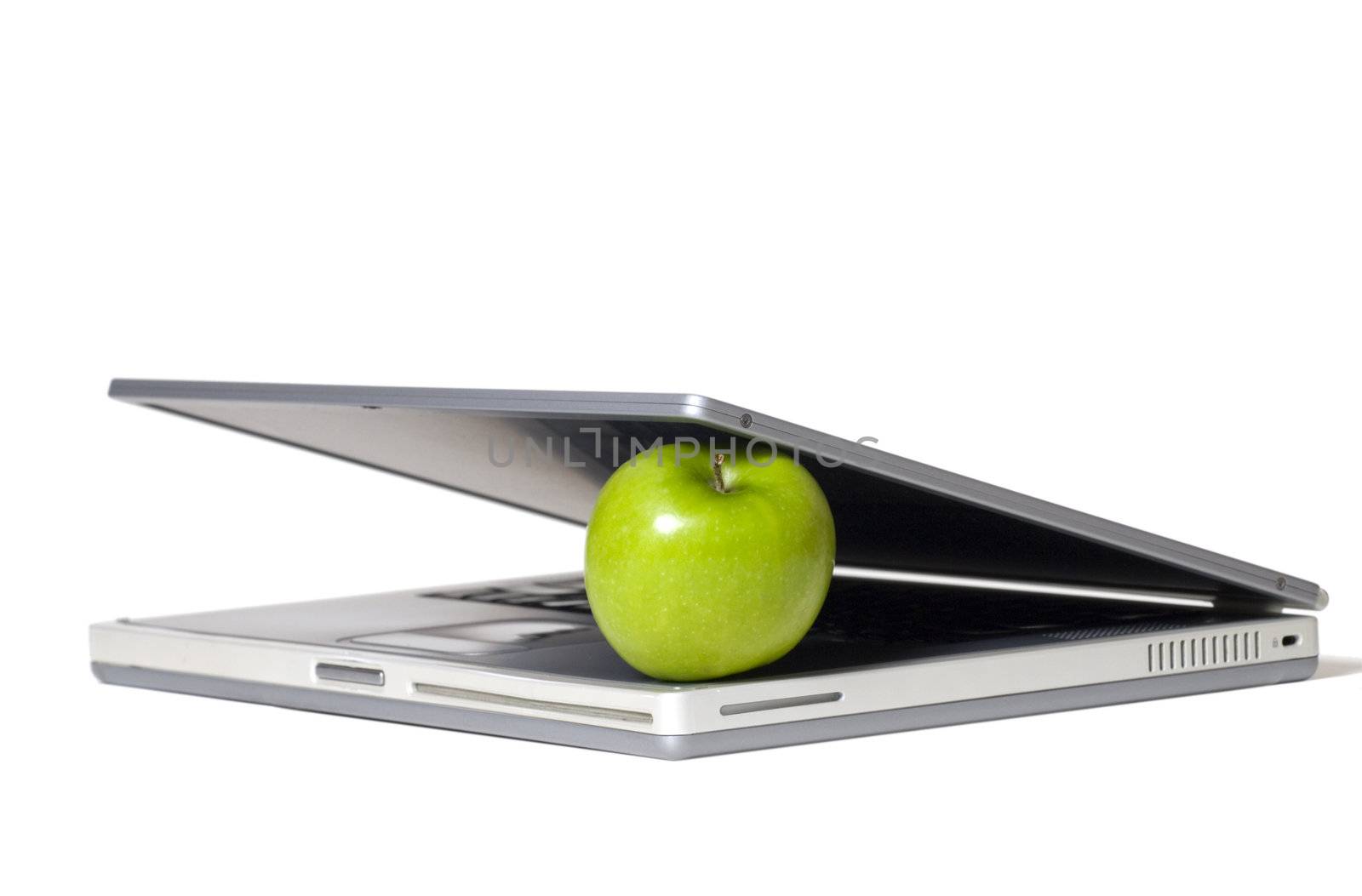 Laptop closing on a green apple - selective focus on the apple.