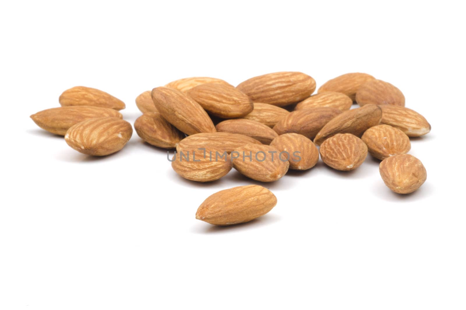 Multiple almonds on a white background with the focus on the foreground almonde