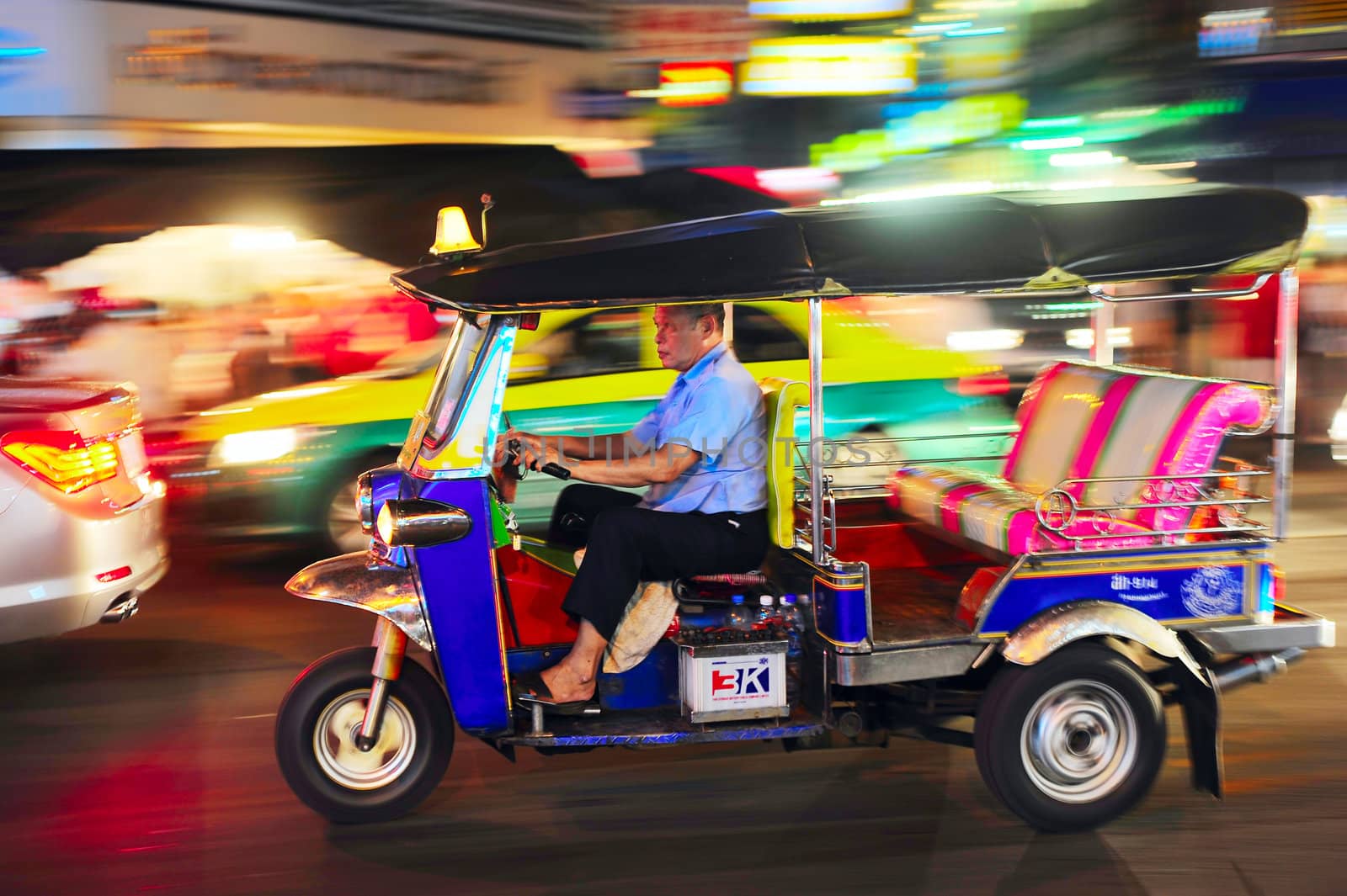 Bangkok, Thailand - March 03, 2013: Tuk - tuk driver riding his tuk-tuk on Chinatown street at night .  There are more than 100,000 "tuk-tuk" in Bangkok.