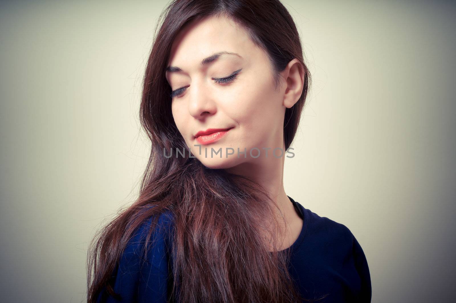 portrait of beautiful girl with long hair and blue sweater on gray background