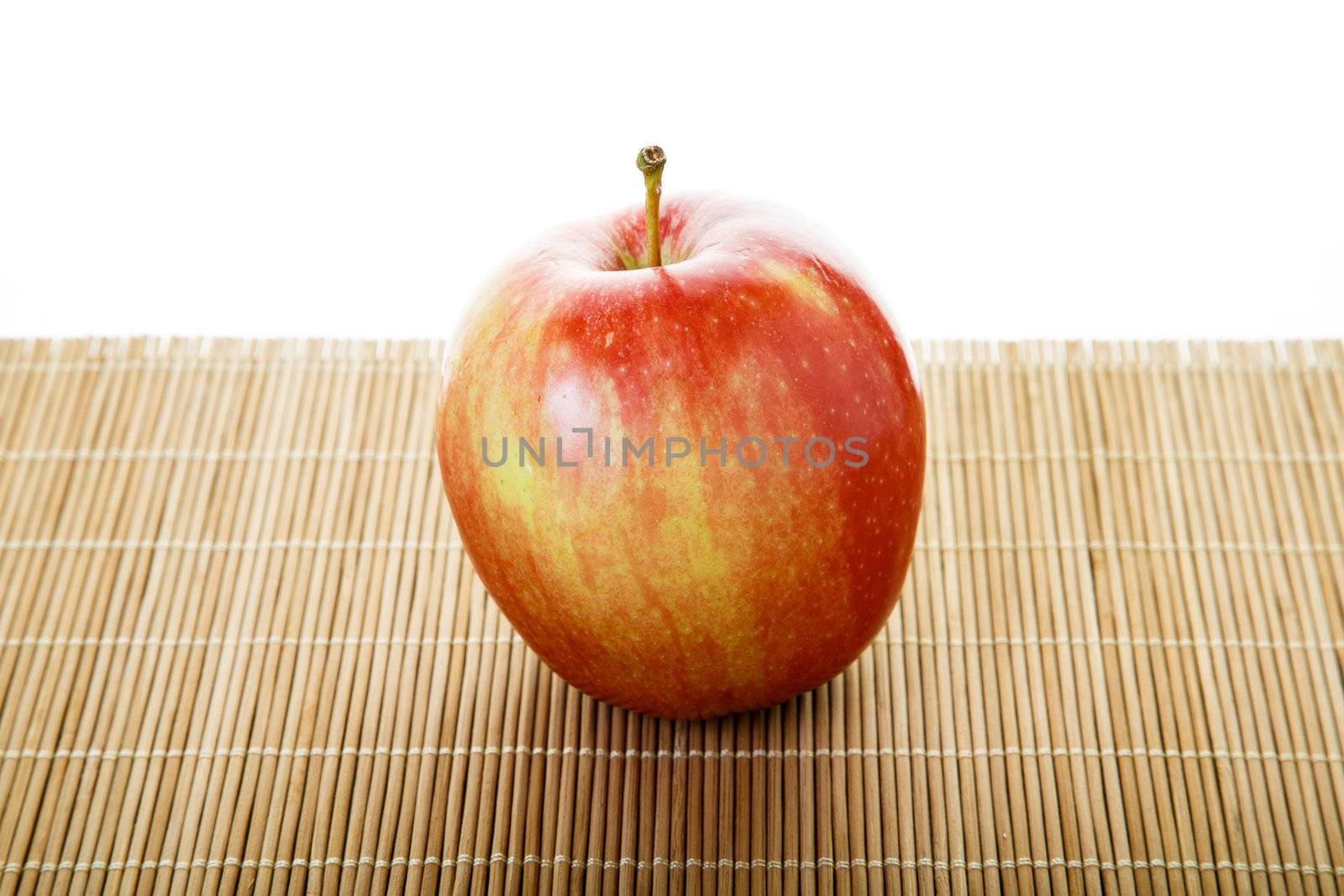 Single red apple on a bamboo mat