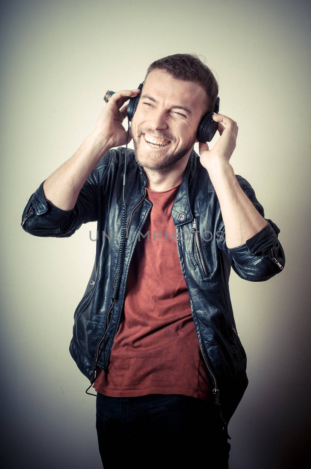 vintage portrait of fashion smiling guy with headphones on gray background