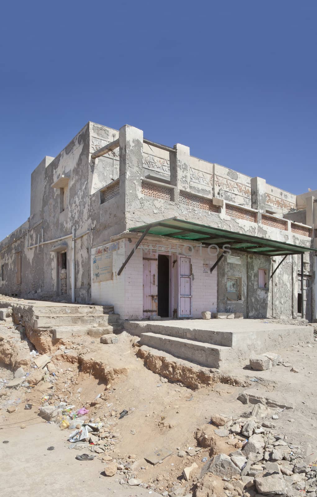 Dwarka Roadtrip February 27 2013. Vertical capture of typical architecture, looking as of ruins with open doors, striking blue sky with rubble, litter and half finished construction that seems typical of Indian culture. Location, Dwarka, Gujarat, India