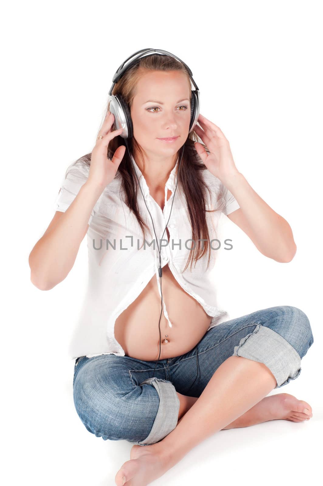 Beautiful pregnant woman with headphones in studio isolated on white