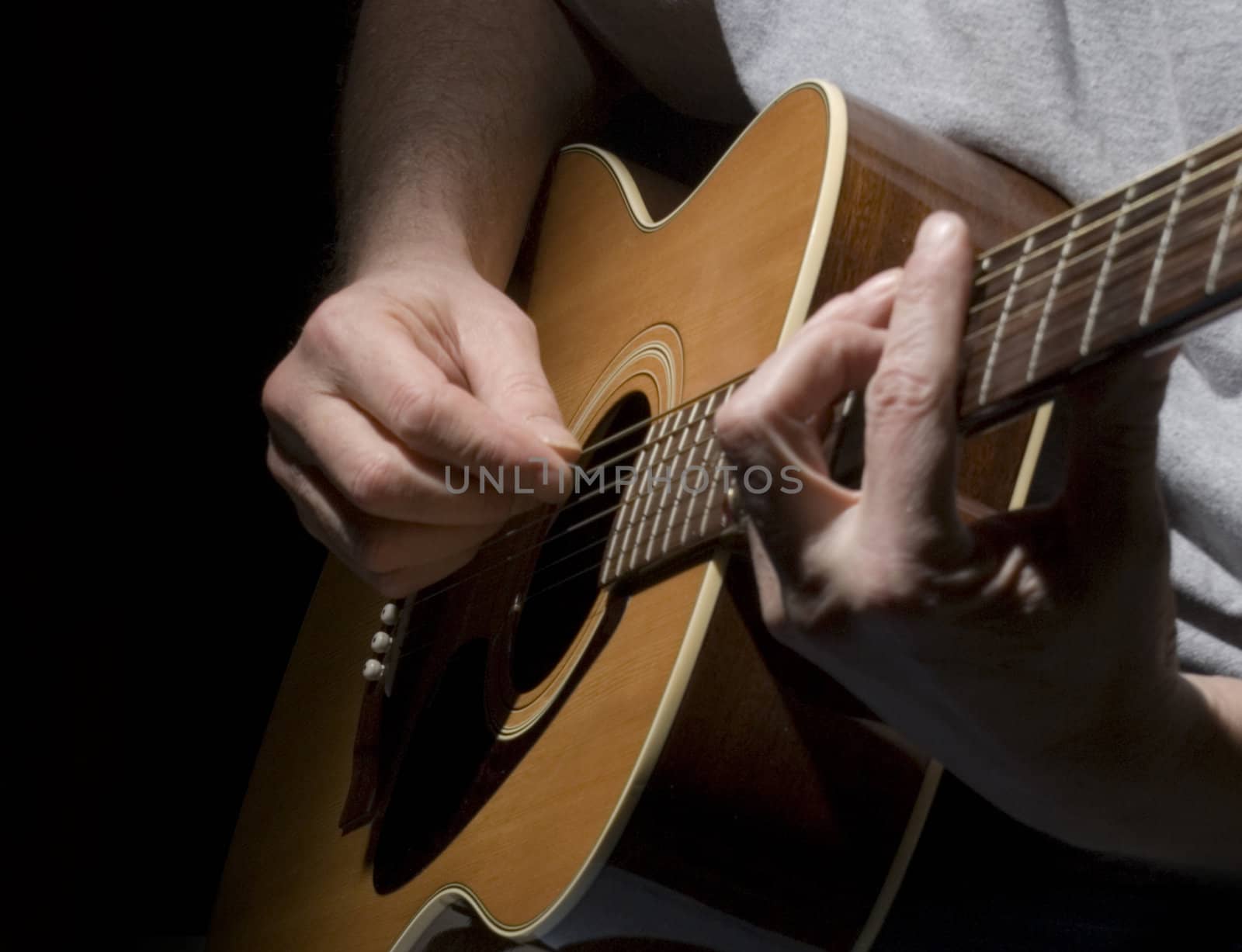 Closeup of guitar and muscian's hands with a black background.