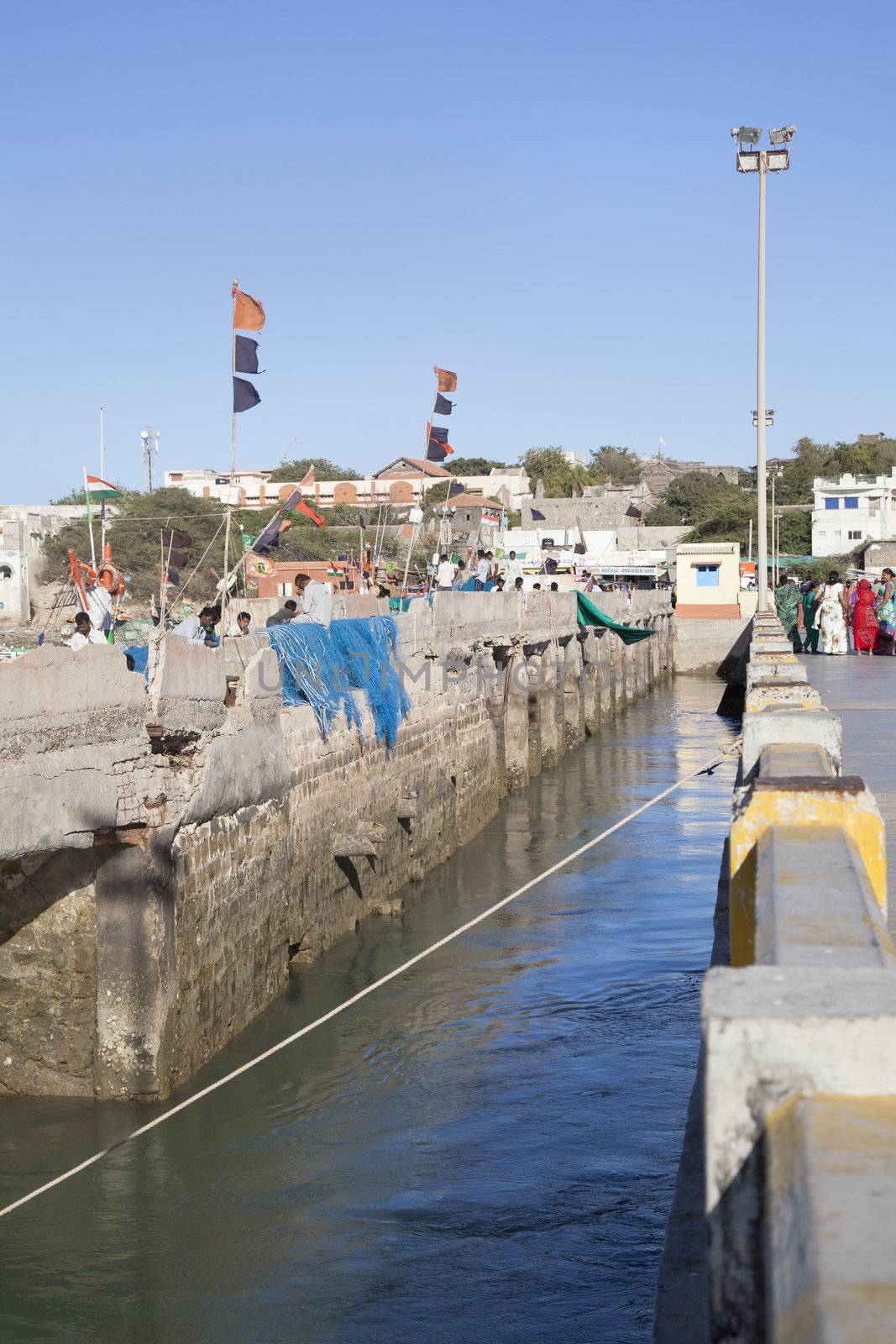 Dwarka Roadtrip, vertical capture of the landing from mainland Indian. Fishnet menders hard at work and general public going about to complete their pilgrimage under the hot sun at Bet Dwarka pier.