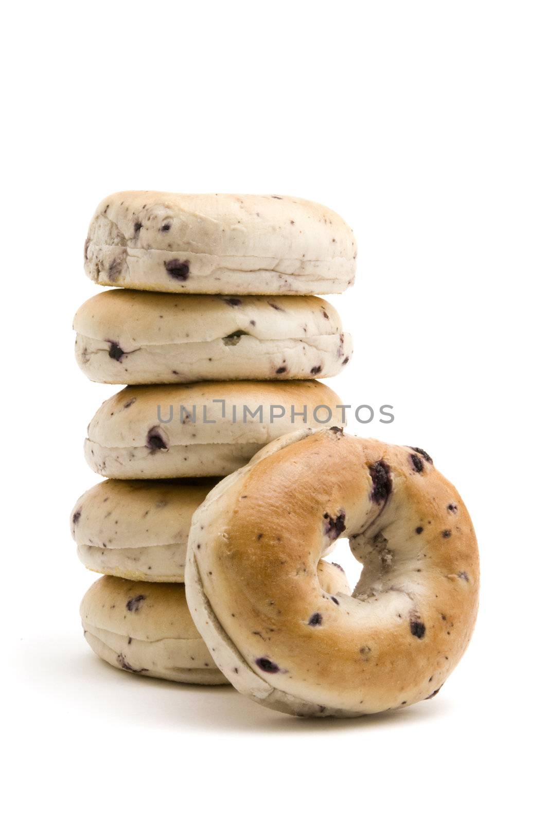 One blueberry bagel resting on a stack of bagels all isolated on white background