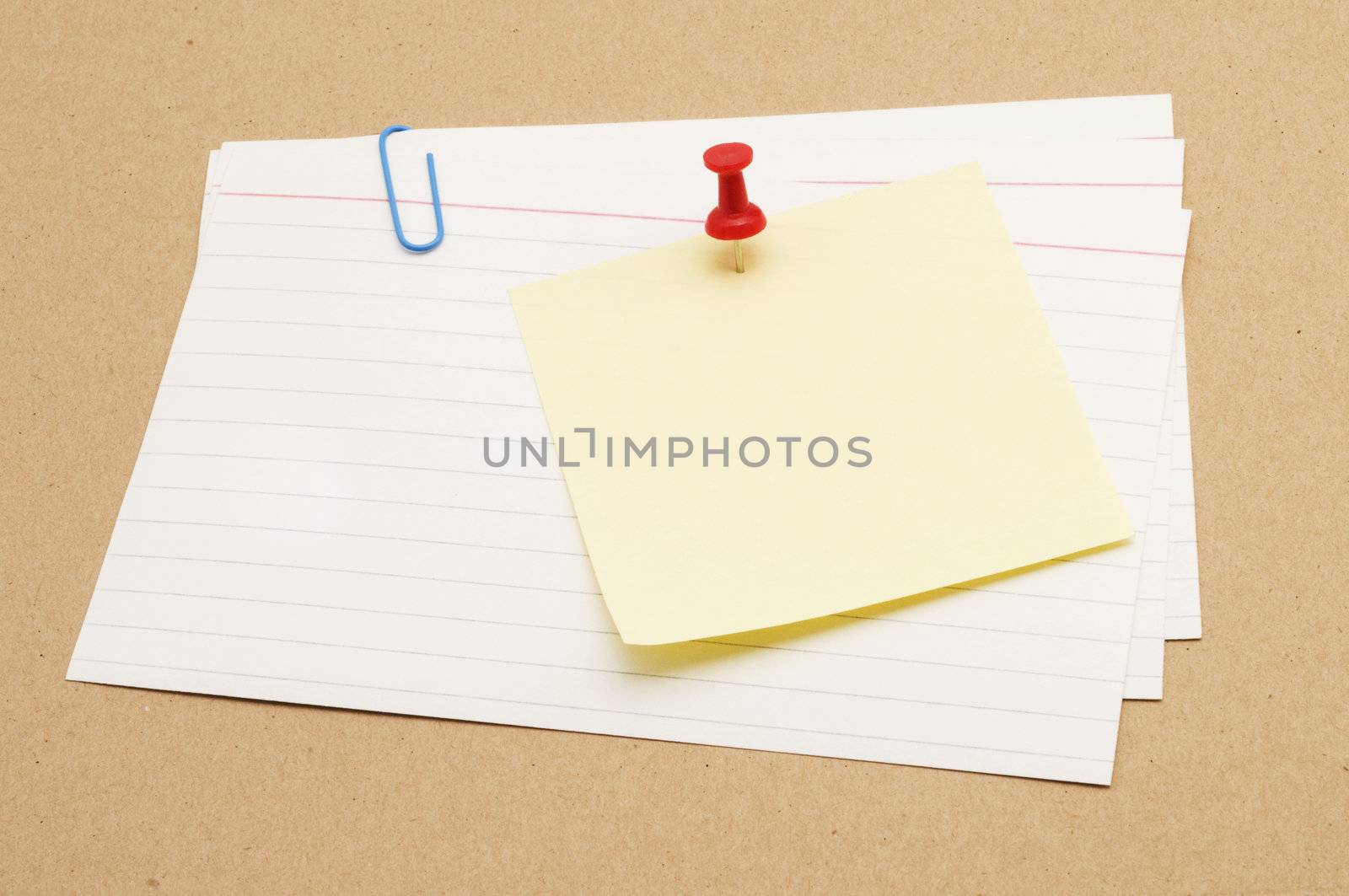 Pushpin holding a sticky note on index cards