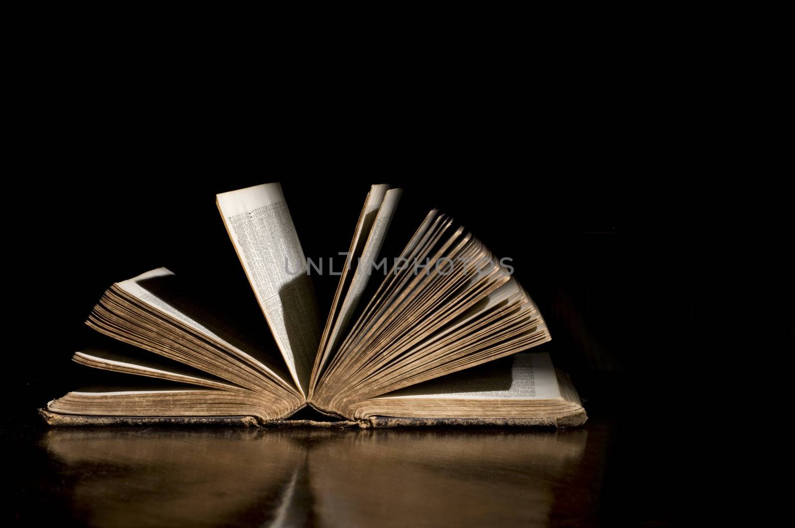 High contrast light on an open antique bible with black background and good copy space
