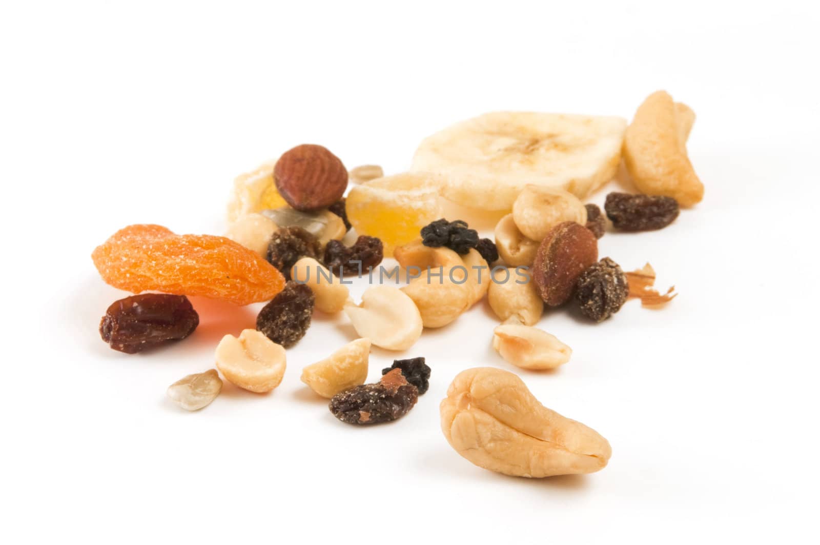 Small amount of trail mix on white background with selective focus on the cashew nut in the foreground