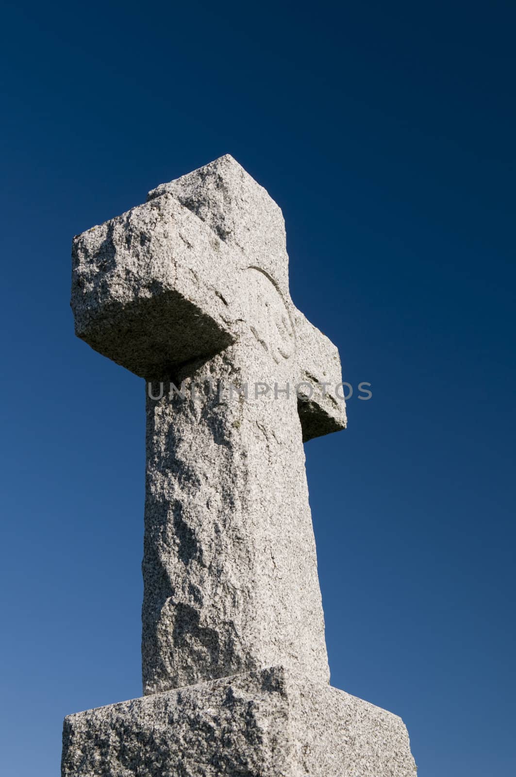 Wide angle image of a stone cross on a deep blue sky