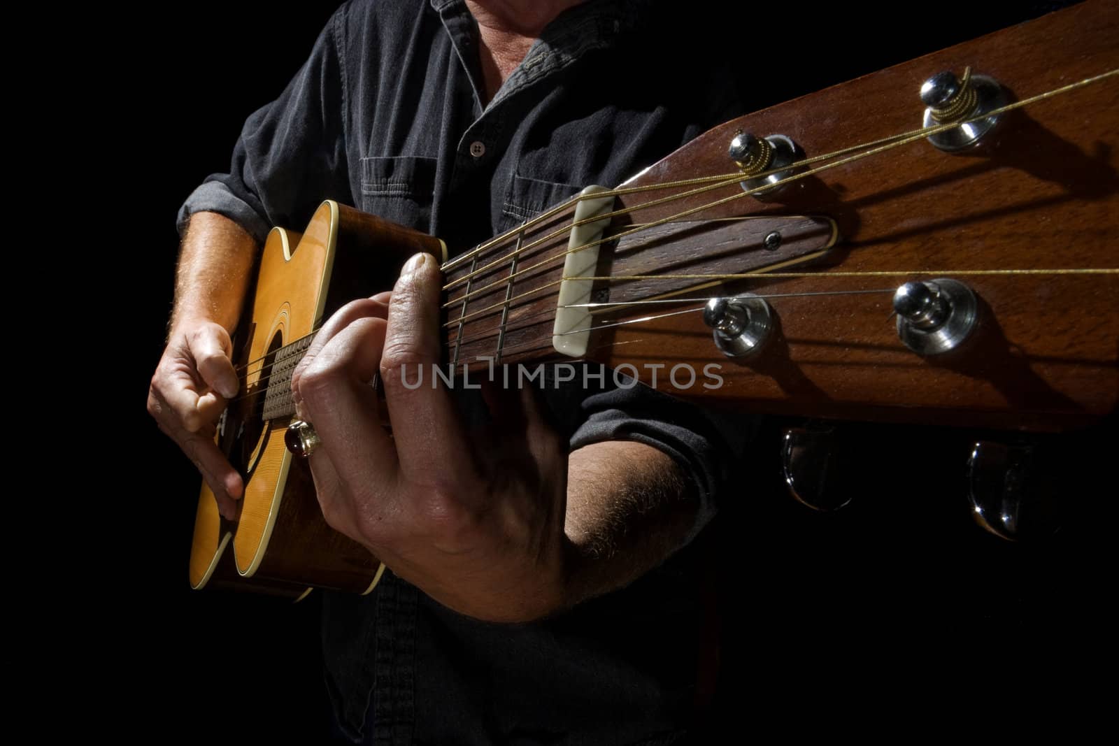 Wide angle photo of a musician playing an acoustic guitar.