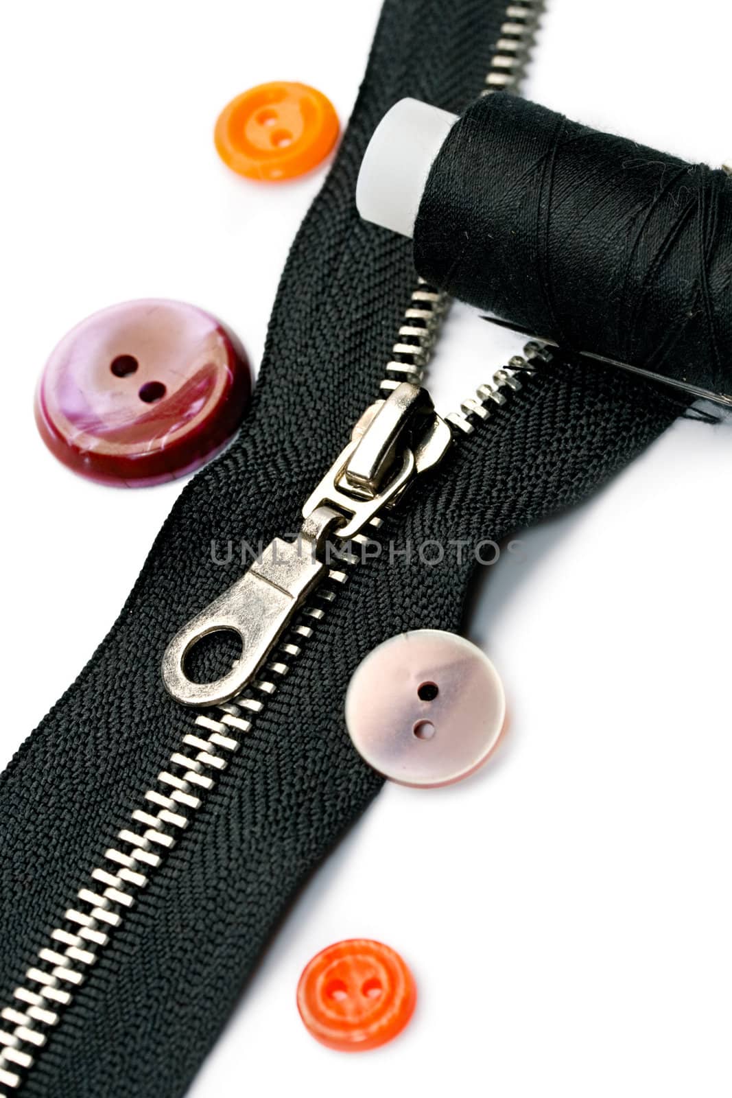 Zipper, thread and button isolated on white