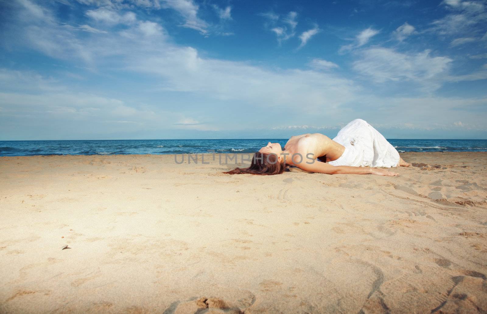 Topless woman laying on sand at the sea. Horizontal photo