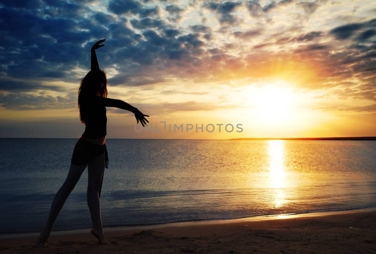 Dancing lady outdoors during sunset at the sea