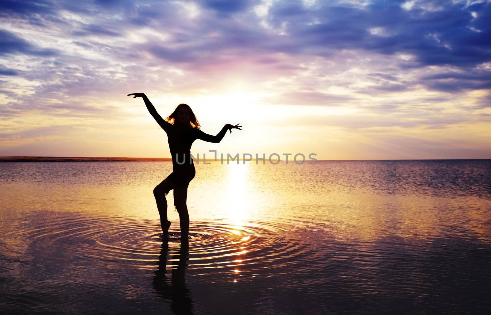 Slim lady standing in the water during sunset