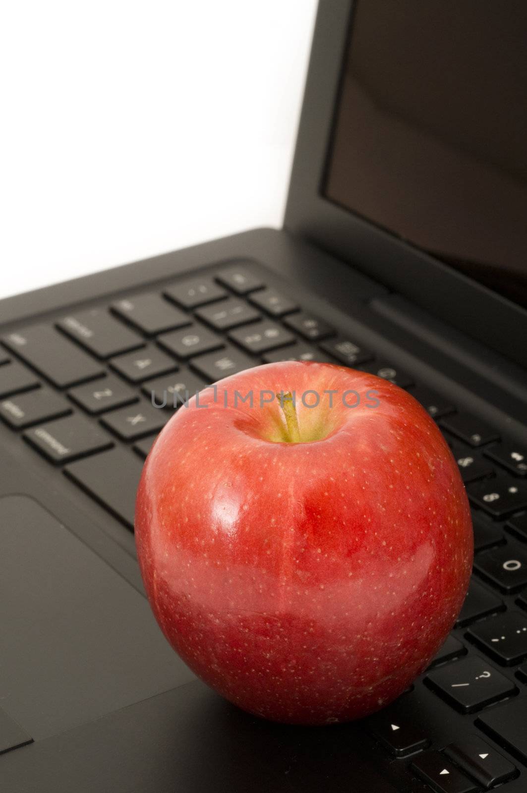 Red apple resting on a laptop keyboard, concept; health, healthy computer