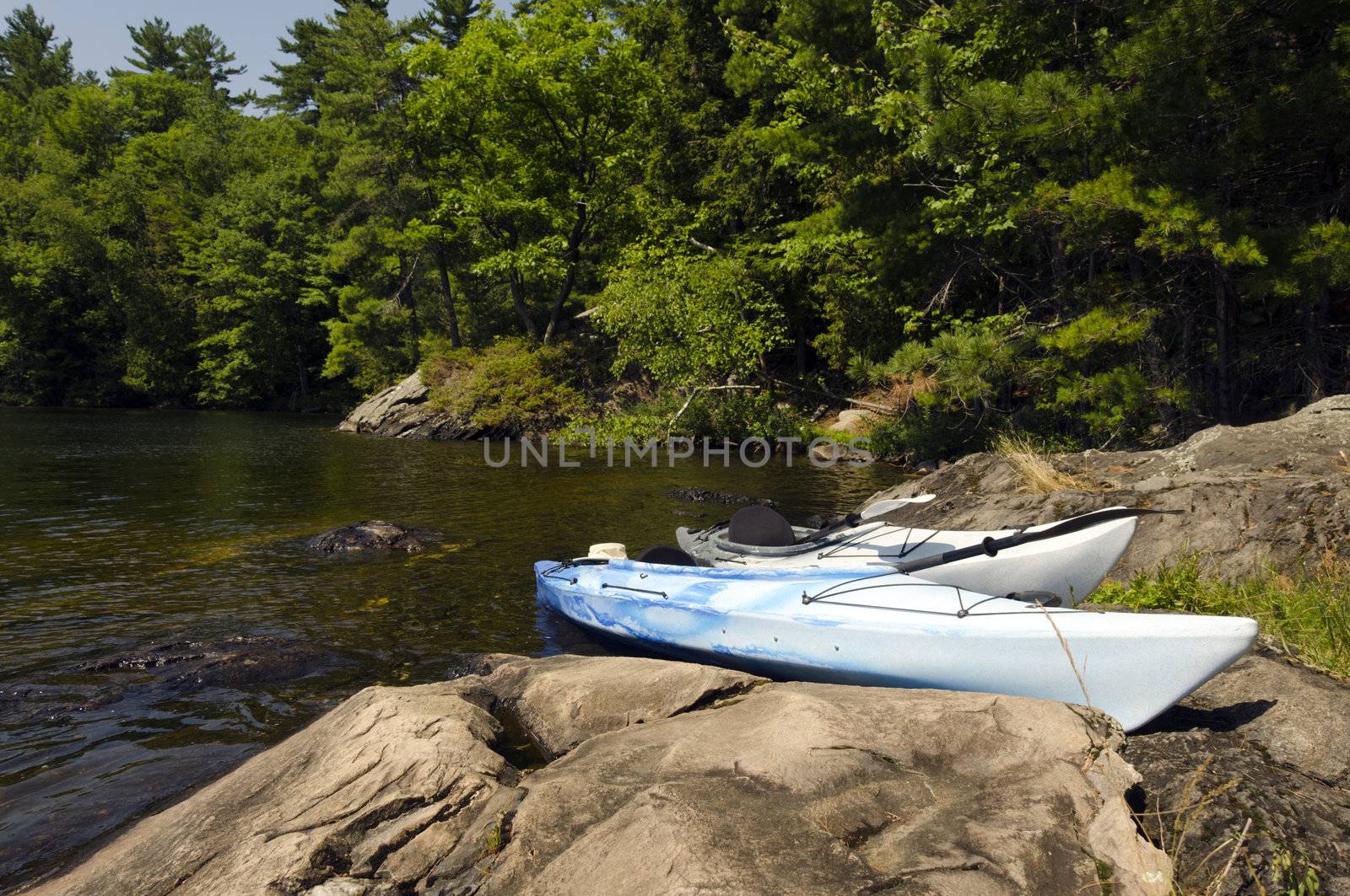 Two kayaks on the rocky shoreline of a northern lake