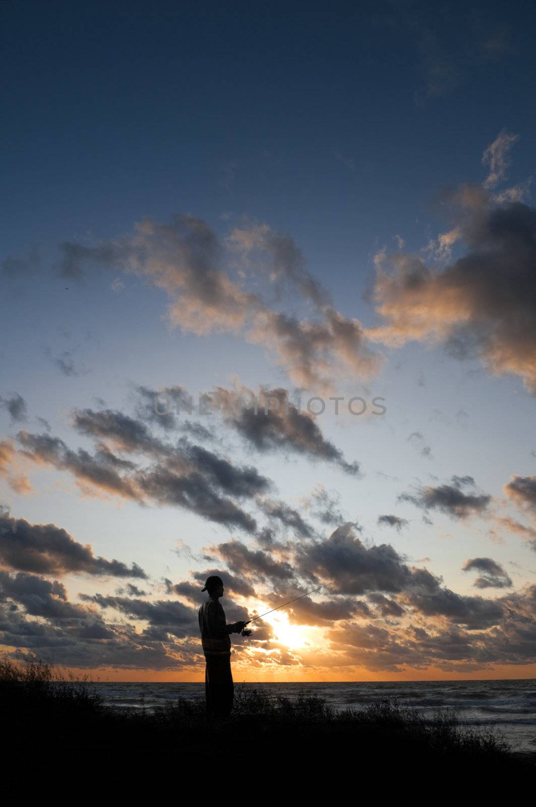 Silhouette of a person walking along the shoreline at sunset in Nova Scotia