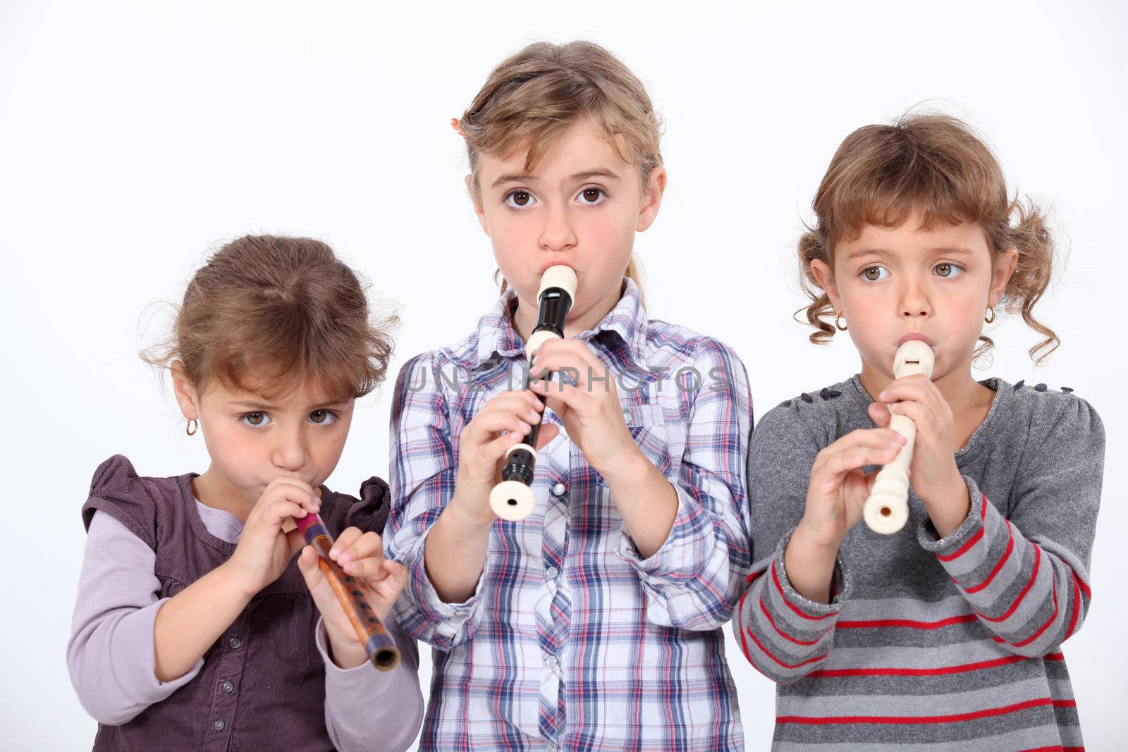 Three young girls playing the recorder