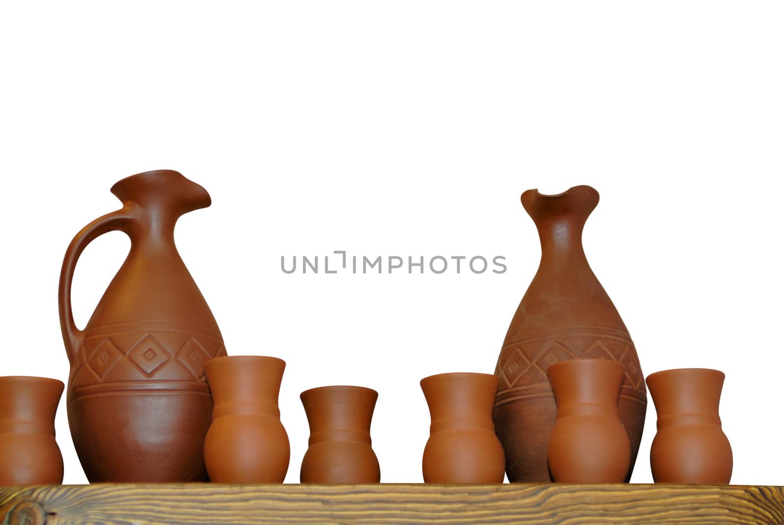 Clay jugs and cups on a shelf isolated on white