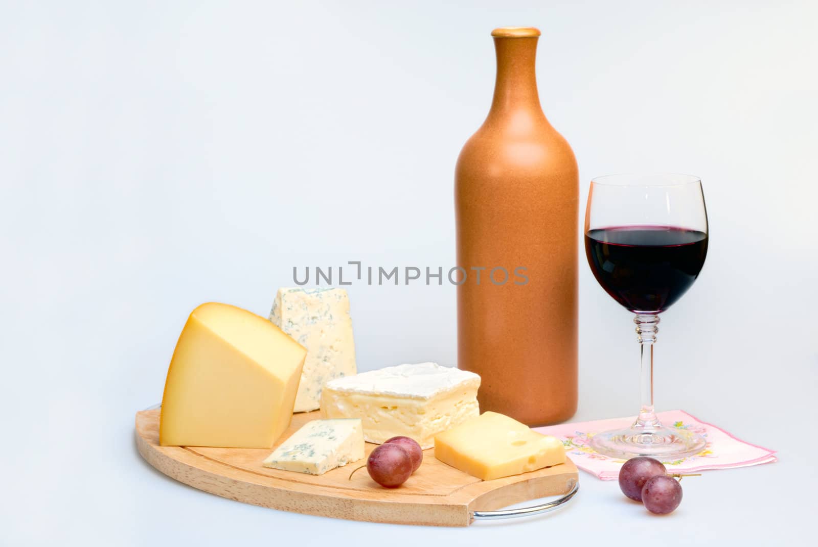 Glass of red wine bottle and cheese plate