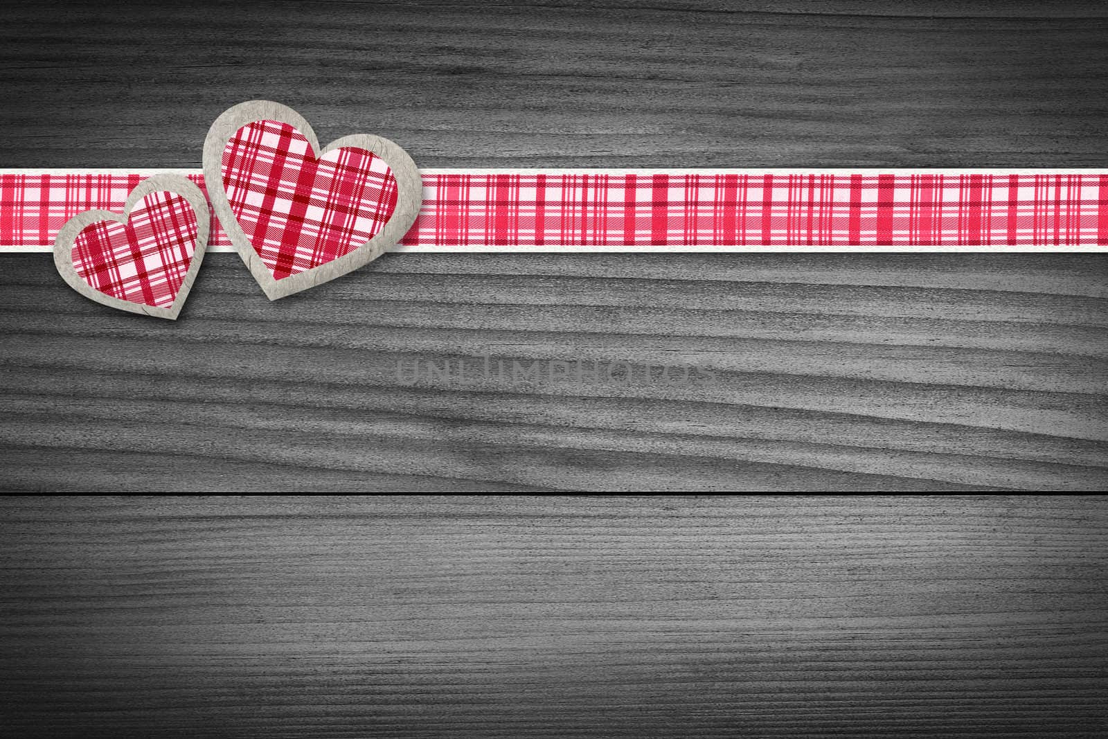 Two hearts and a red checkered texture stripe laying on wood.