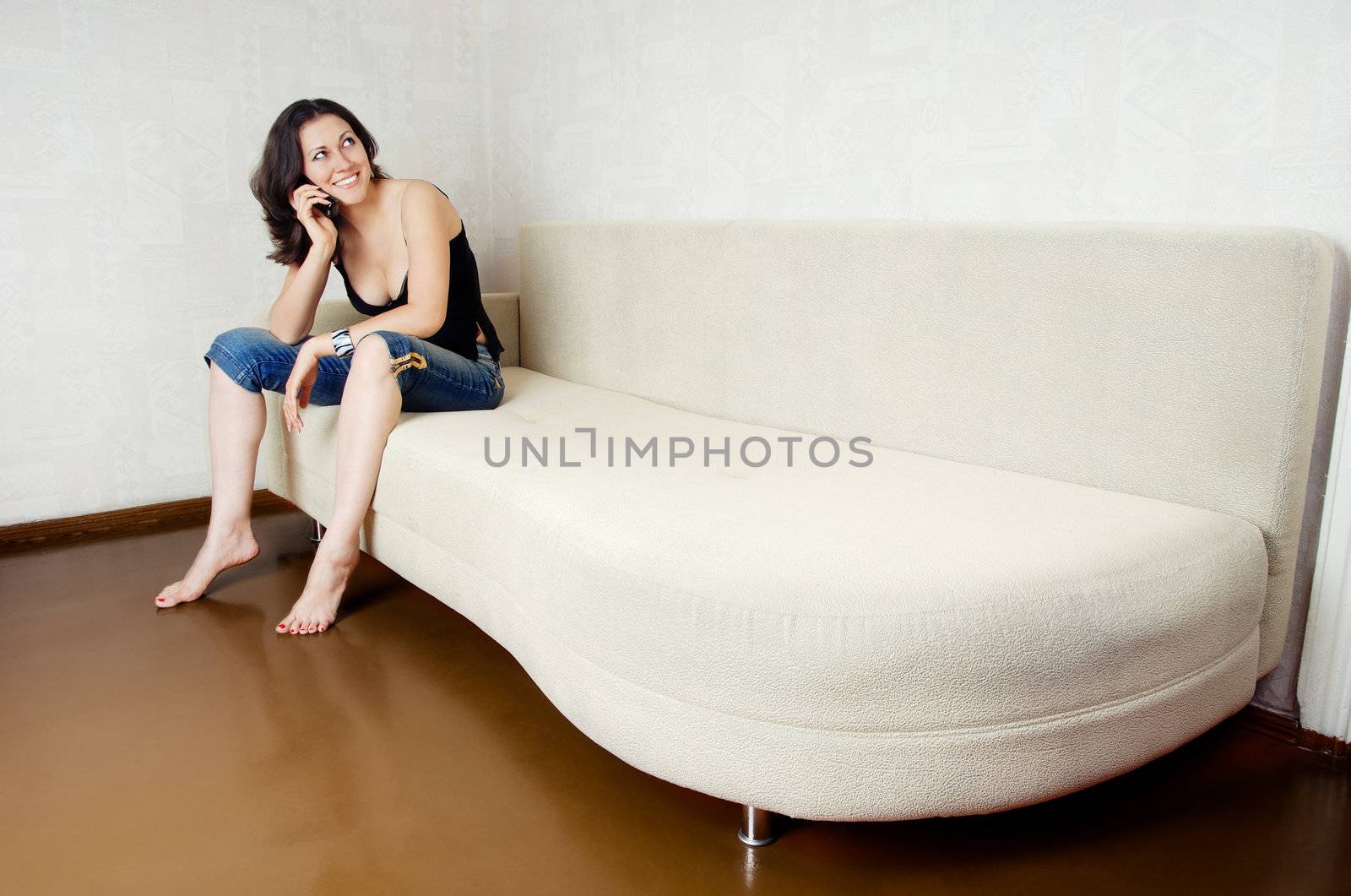 Photo of the cheerful lady sitting on a sofa with phone