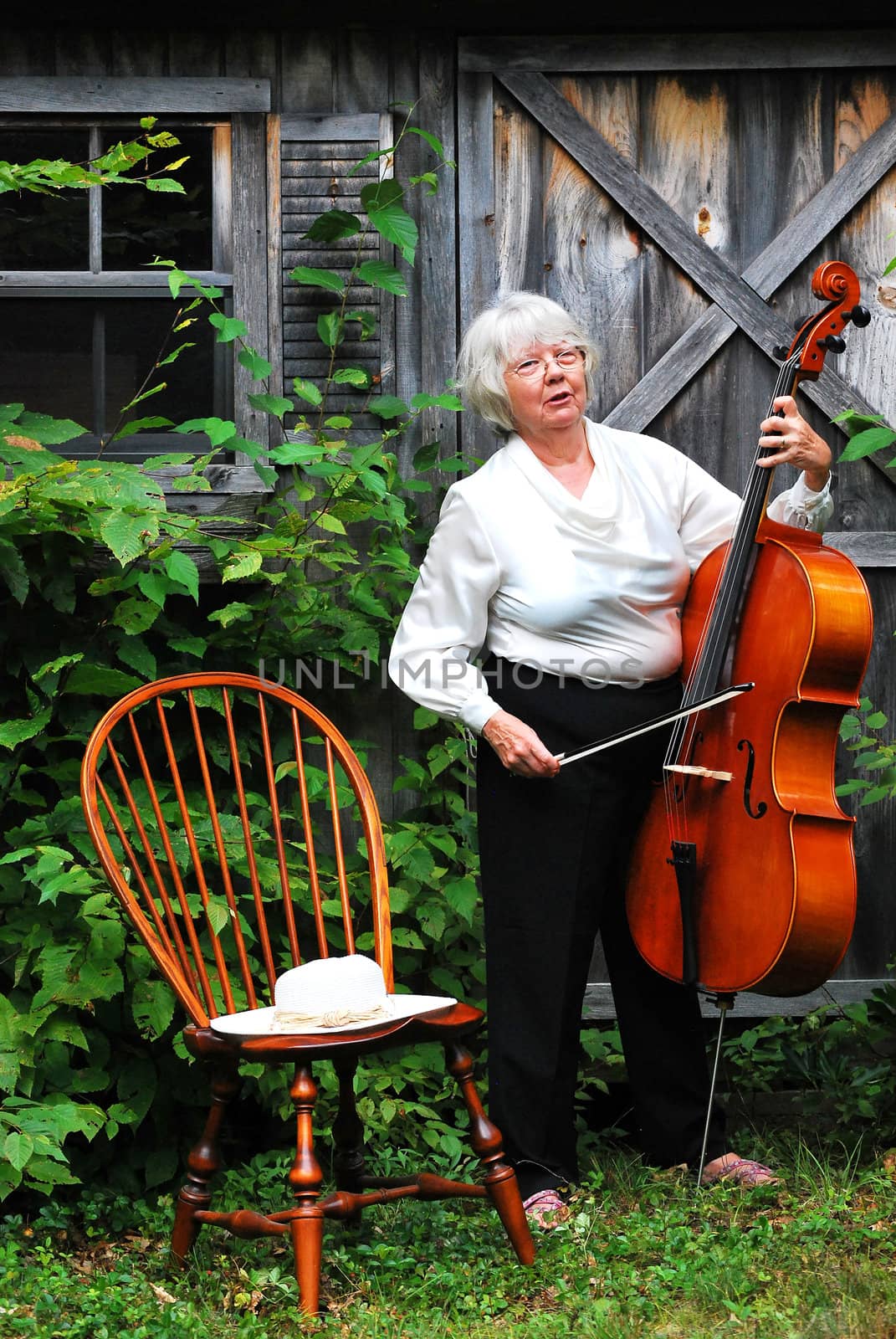 Female cellist standing with her cello outside.