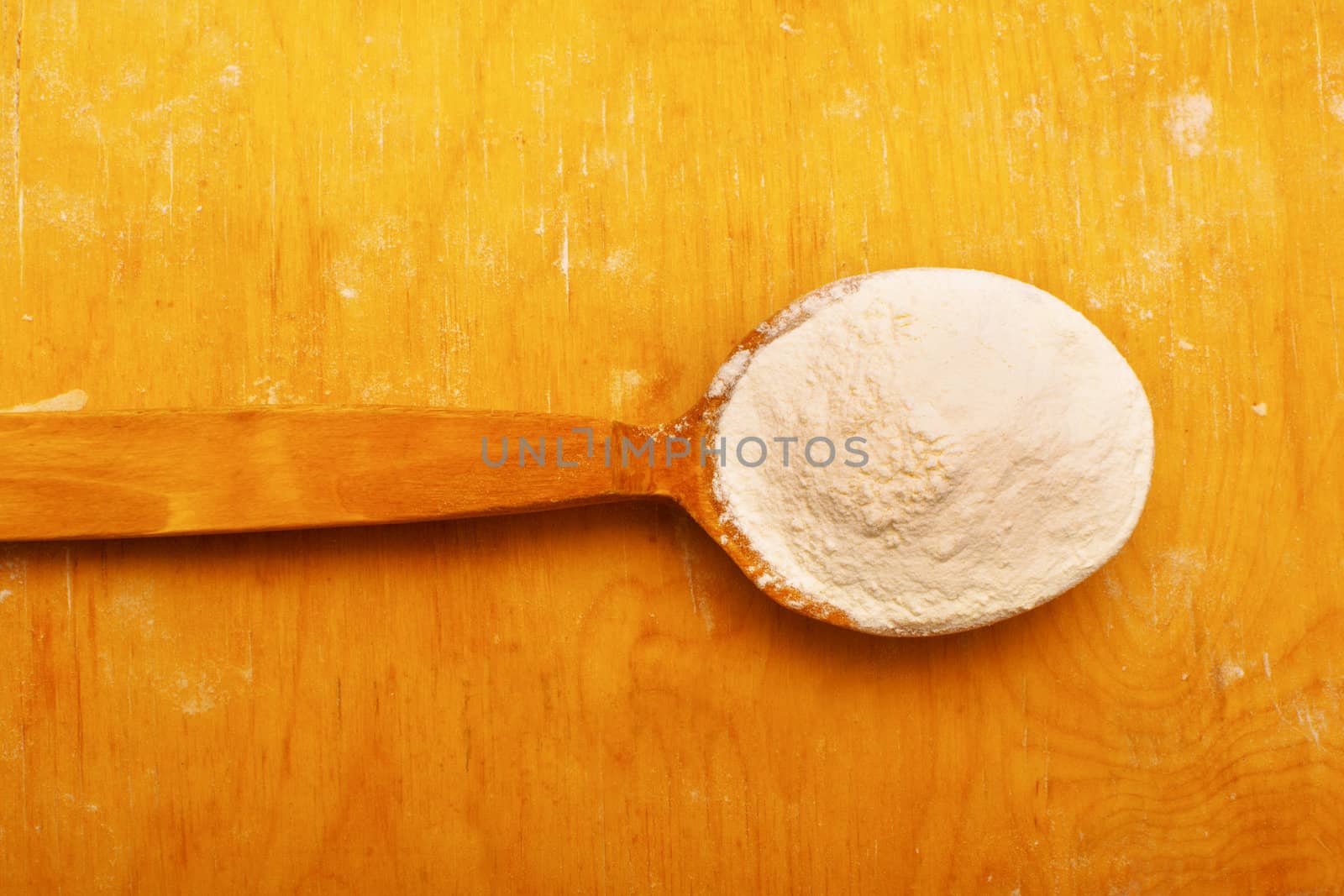 Whole flour in spoon on rustic wooden background