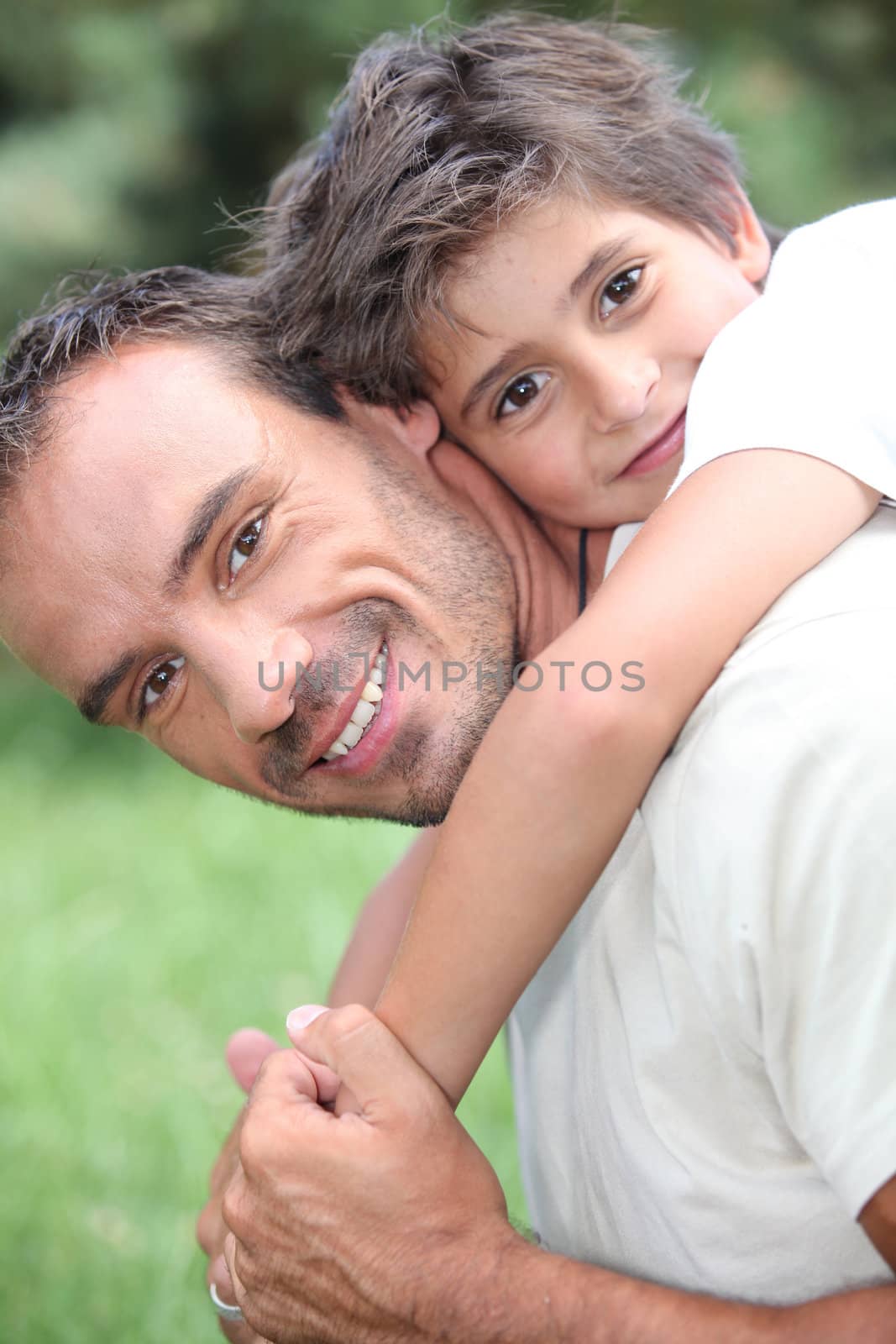 Father giving son piggy back outdoors by phovoir