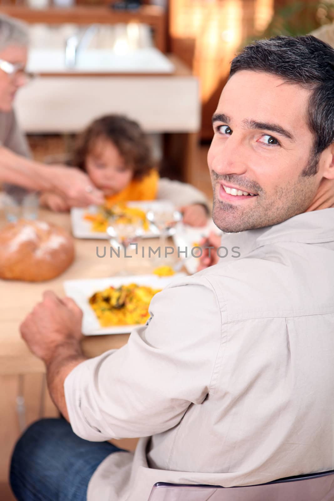 Family gathered around kitchen table by phovoir