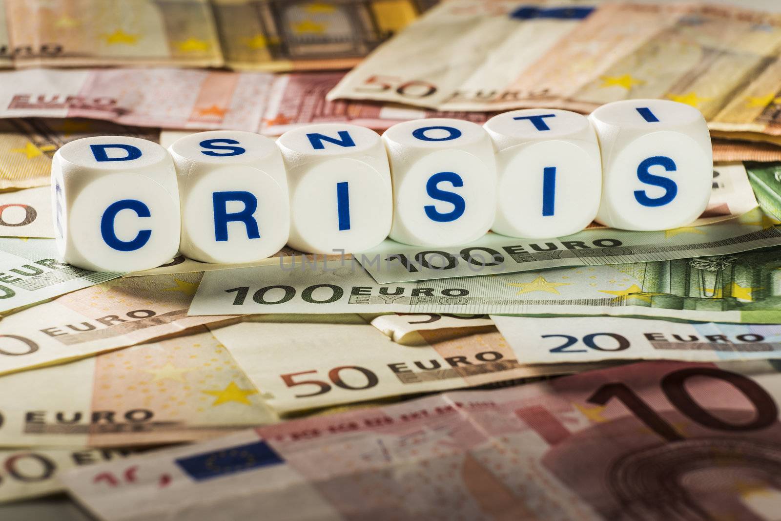 Letters on white cubes with the word crisis on euro banknotes