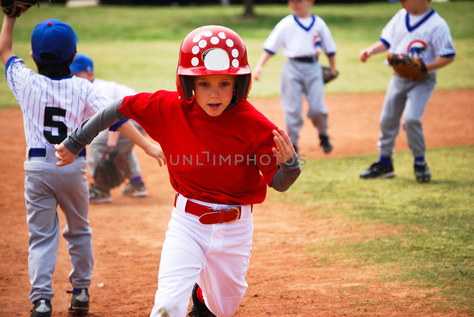 Youth little league baseball boy running bases.