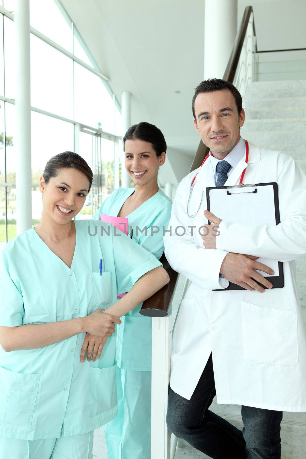 Doctor and two nurses standing on a staircase in a hospital by phovoir
