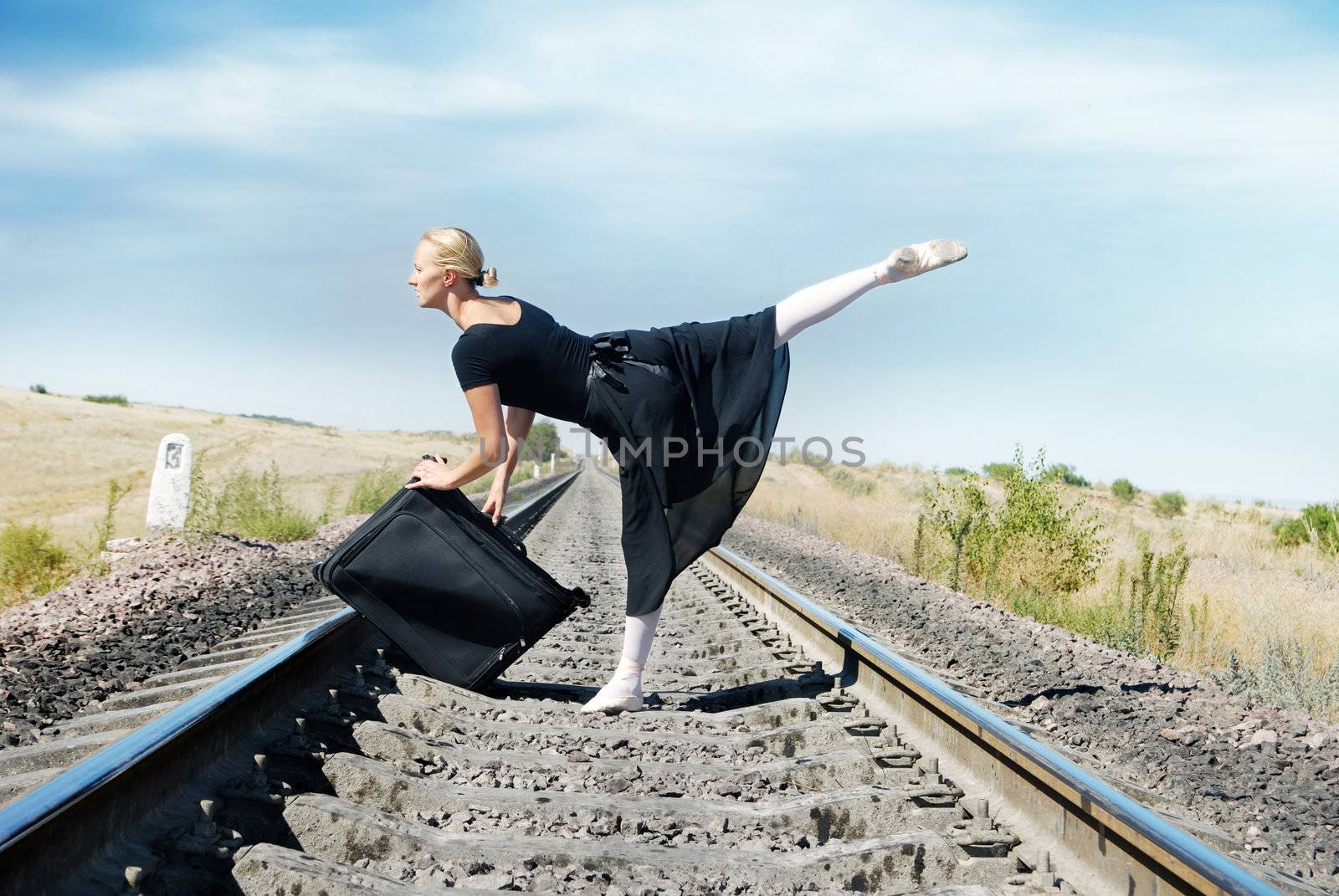 Ballet dancer with suit-case on the railway going to the travel