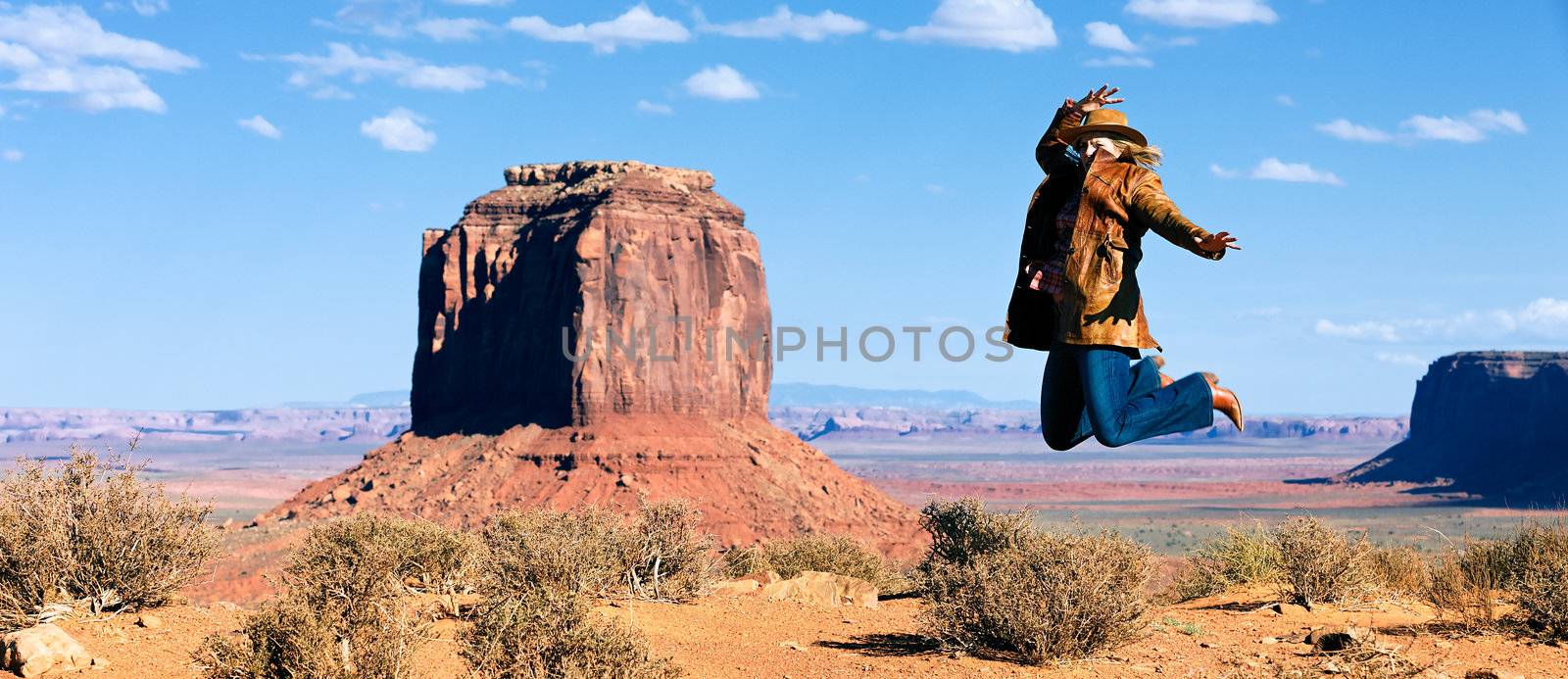 panoramic view of cowgirl jumping in front of Monument Valley, Utah, USA