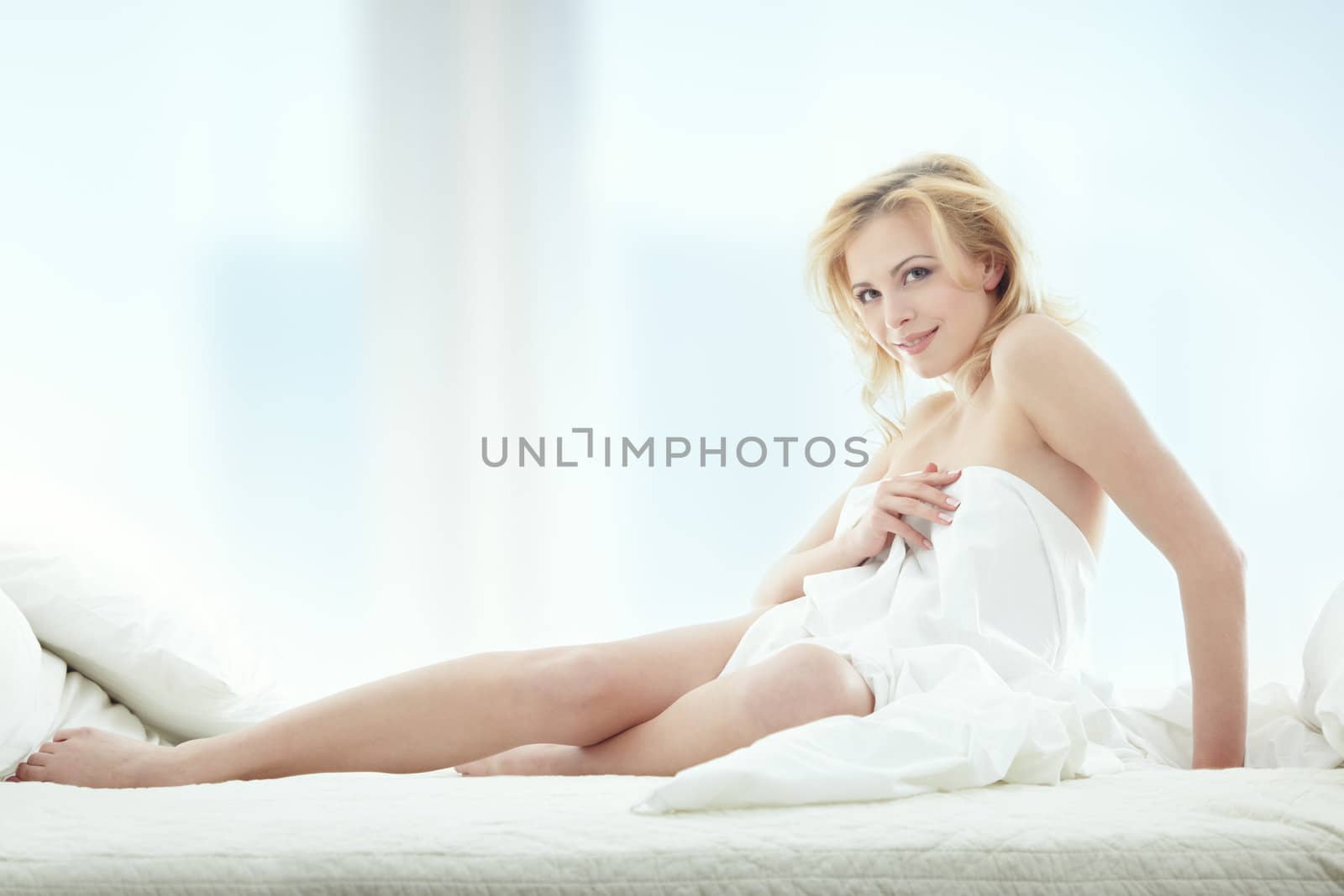 Happy blond lady indoors sits in the bedroom