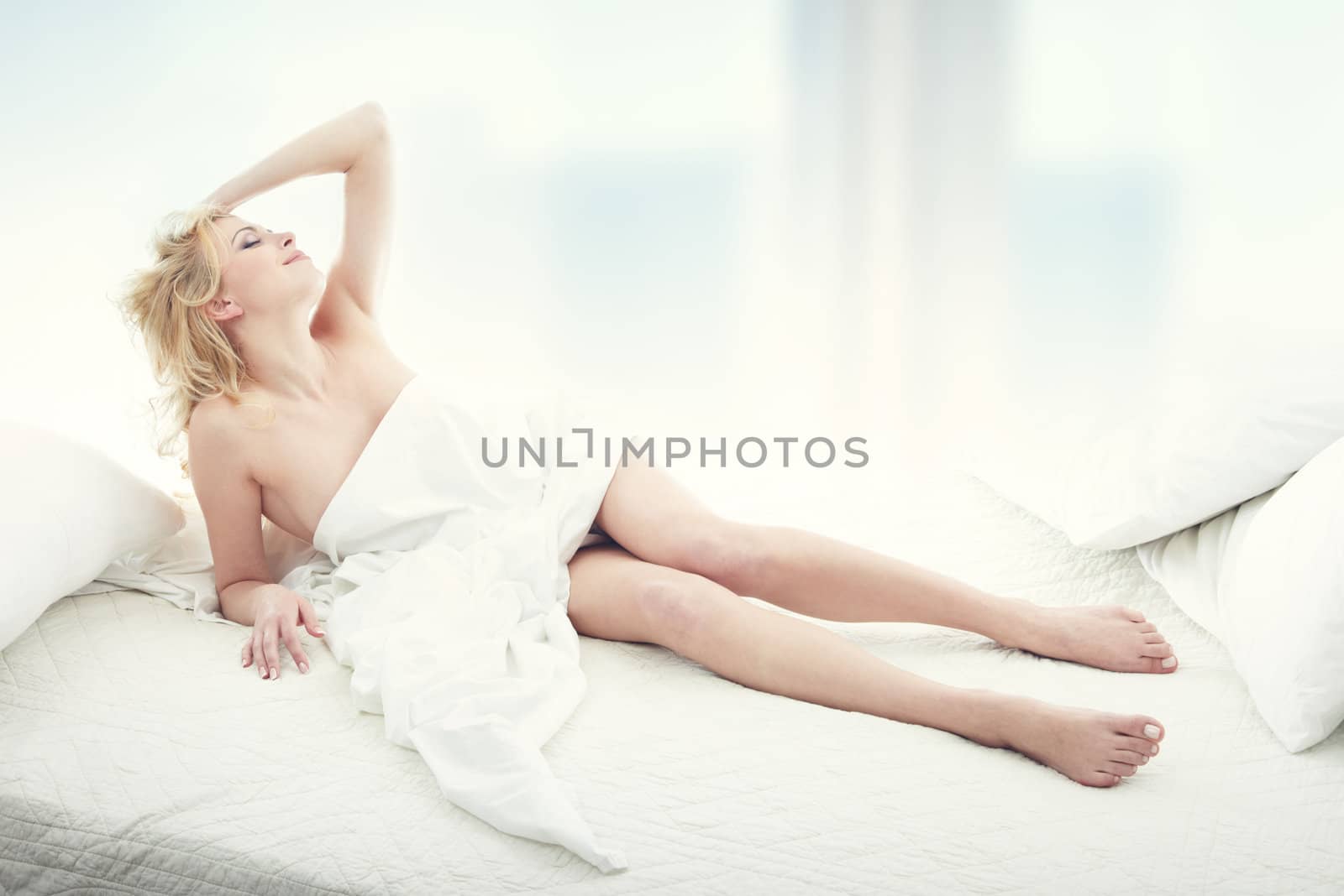 Happy blond lady indoors lays in the bedroom