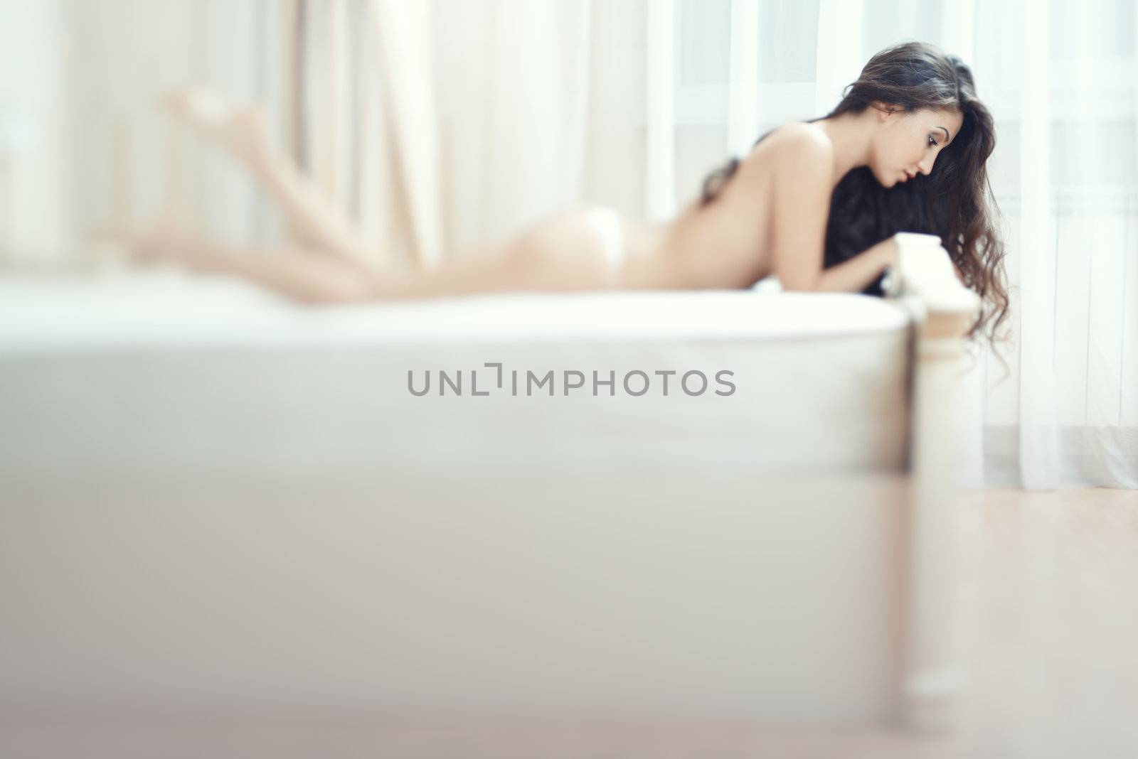 Attractive lady laying on the bed. Creative defocus effect mady by tilt shift lens