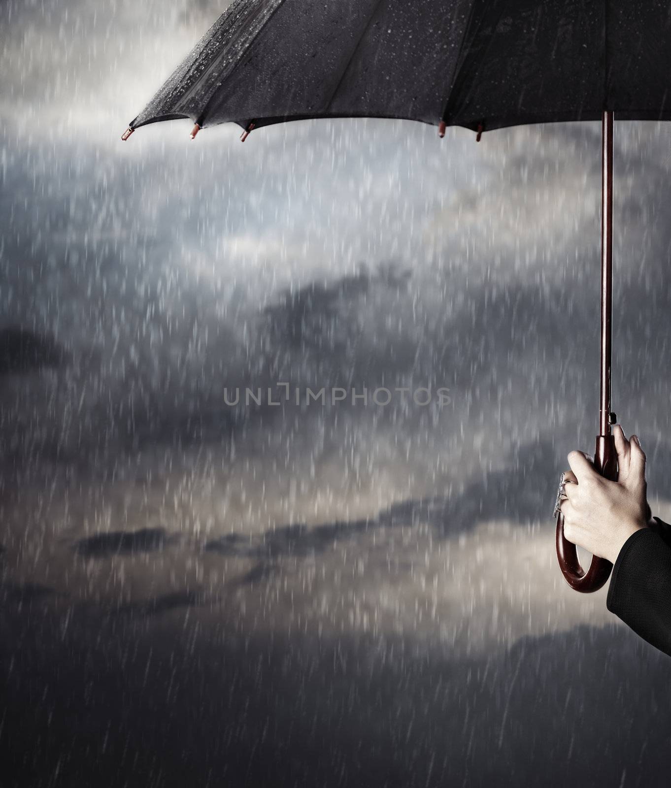 Human hands holding big black umbrella under the heavy rain