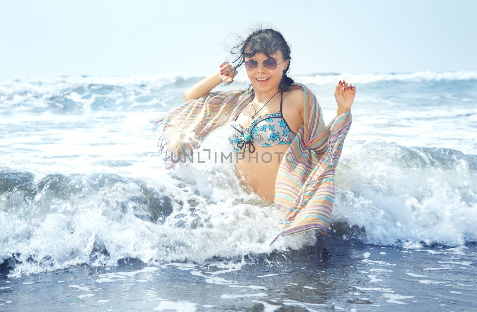 Happy brunette lady in the sea playing with waves