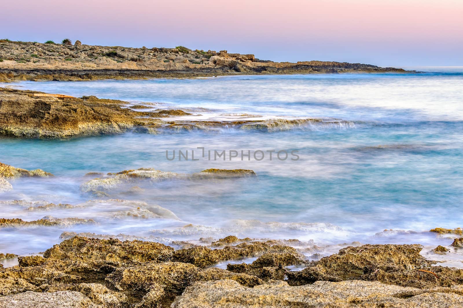 Susnset over rocky coast with motion blurred sea surface