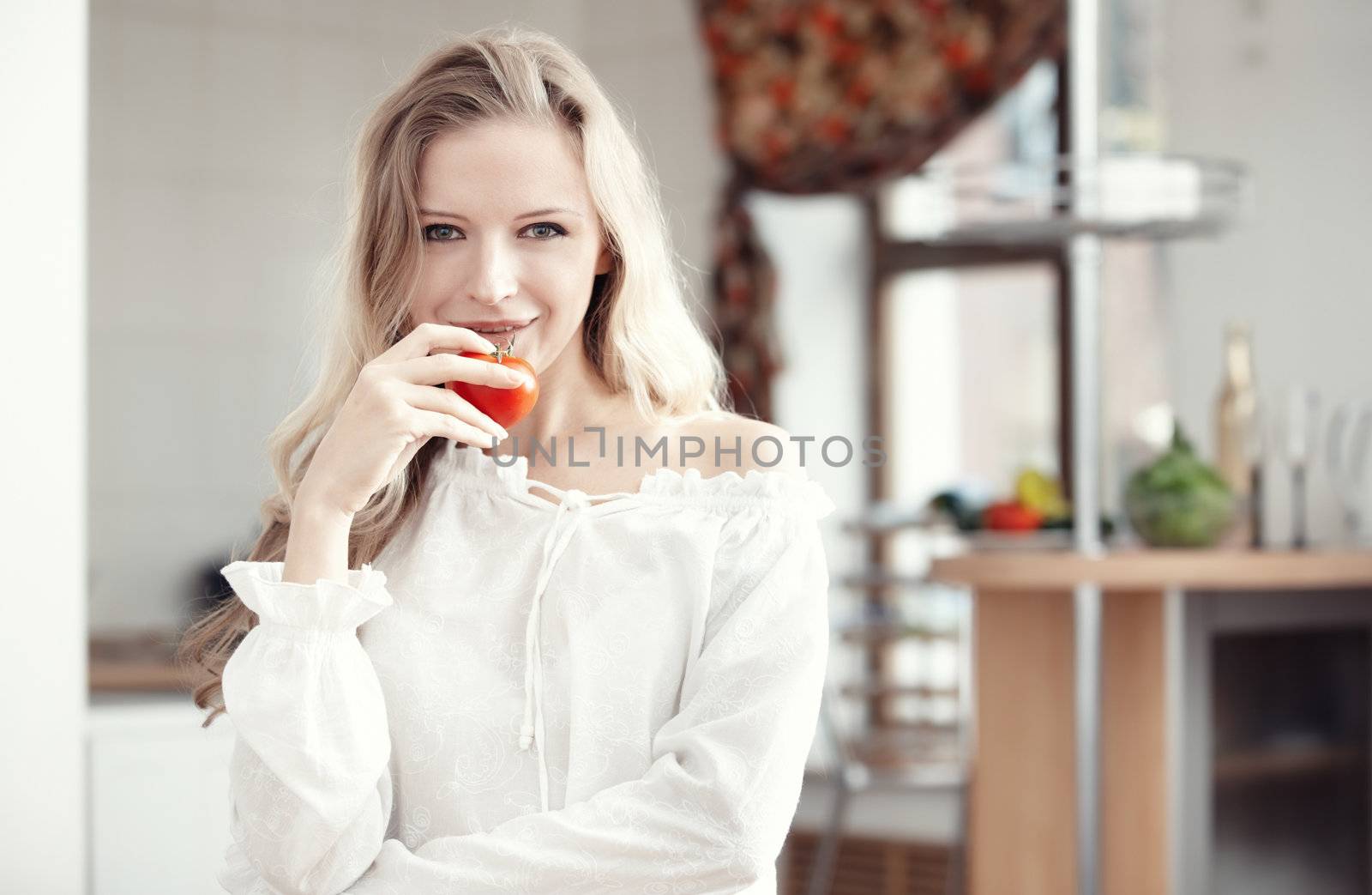 Blond lady with ripe tomato at the kitchen